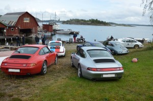 Bild från Yxlö som ligger vid havet utanför Stockholm. Porschar i olika färger står parkerade vackert vid havet.